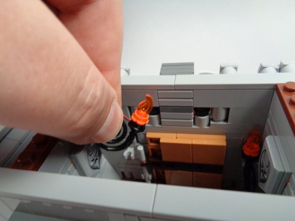 As shown in the first photo for this step, re-attach the second torch and run its wire behind the inner wall section and up out the top of the hall (like you did with the first torch).