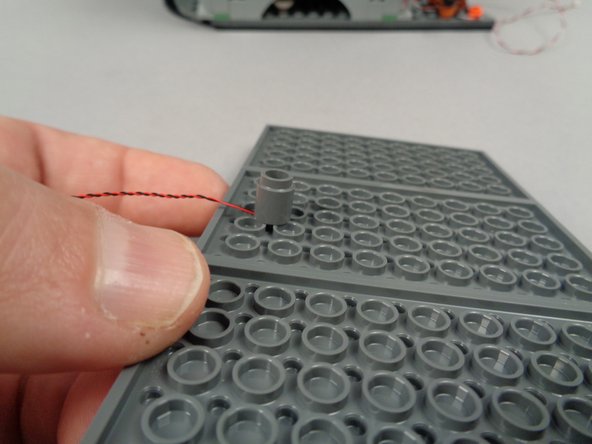 As shown in the photos for this step, attach the round brick to the center rear of the middle plate under the roof.  The light should be positioned at the back of the town hall so it sits above the podium when the roof is re-attached.