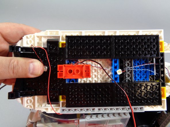 The purple arrows in the second photo show how the light wires are kept away from the gears by the red bricks of the roof motor.