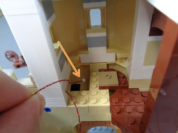 As shown in the first photo for this step, feed the light wire down under the spinning room floor.  Pass the wire all the way down.