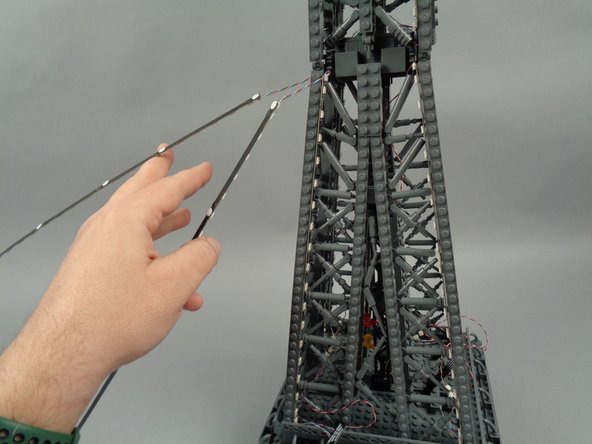 Remove the backs of the sticky dots on the second light strip (connected to plug #2 of the adapter board), and attach the strip to the tower frame as shown in the photos for this step.