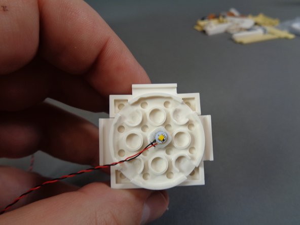 As shown in the third photo, you will need to do more disassembly of the turret to allow the LED light wire to pass down into the body of the castle.