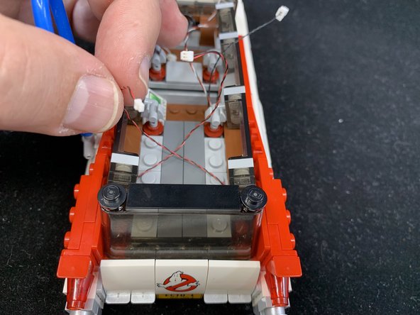 As shown in the first photo, the two tail light wires should extend into the rear section of the Ecto-1.