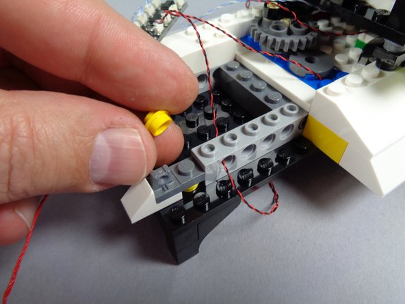 As shown in the first photo for this step, remove the yellow round 1x1 LEGO plate from the roof.