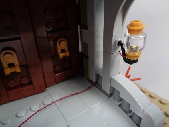 As shown in the photos for this step, run the light wire around the post under the railing and toward the front entryway.