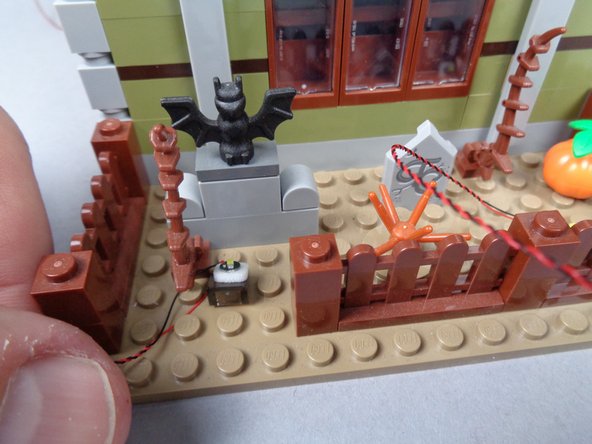 As shown in the third photo, re-attach the fence section with the wires for both LED lights extending to the left.