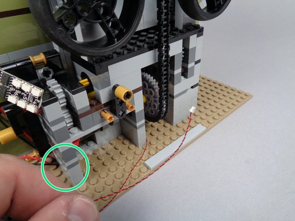 As shown in the second photo for this step, pull the wire all the way through the back of the elevator shaft.