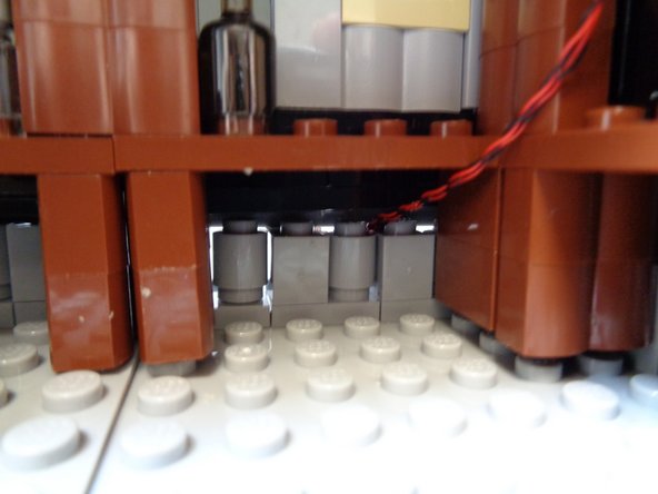 As shown in the first photo, re-attach the 1x1 round LEGO® brick you removed to make room for the attic light wires.