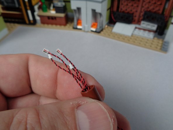 As shown in the second photo for this step, pass the four LED light wire plugs through the center of the brown LEGO connector.