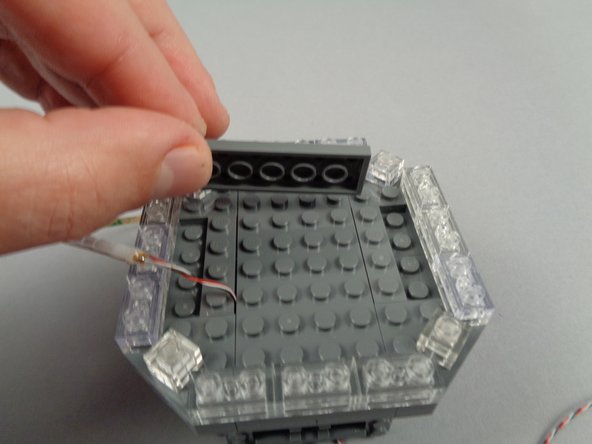 As shown in the photos for this step, use the remaining LEGO plates from the parts bag to extend the height of the center section of the broadcast tower by one plate.