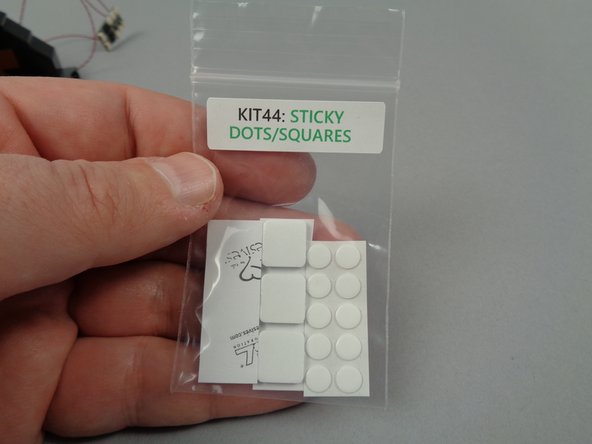 As shown in the photos for this step, remove the sheet of small sticky dots from the small Sticky Dots/Squares bag (provided inside Bag 1), and attach one dot each to the back side of the yellow LED lights.