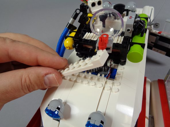 As shown in the first photo for this step, re-attach the white plate on top of the white roof slope.  This will secure the white roof slope into place once again.