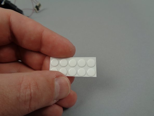 As shown in the photos for this step, remove the sheet of small sticky dots from the small Sticky Dots/Squares bag (provided inside Bag 1), and attach one dot each to the back side of the yellow LED lights.