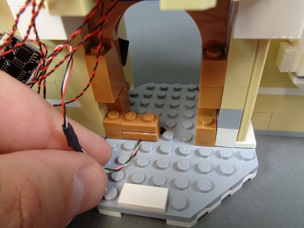 Before you begin re-assembling the stove, make sure the wires for the candelabra and for connecting beneath the castle midsection are running toward the front of the castle as shown by the green arrows in the first photo.