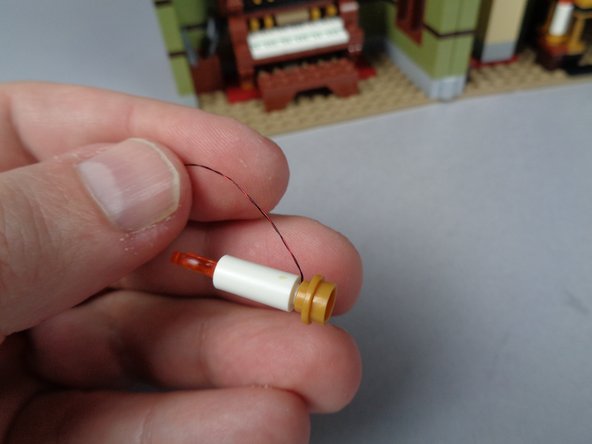 As shown in the third photo for this step, carefully re-attach the gold candle base plate.