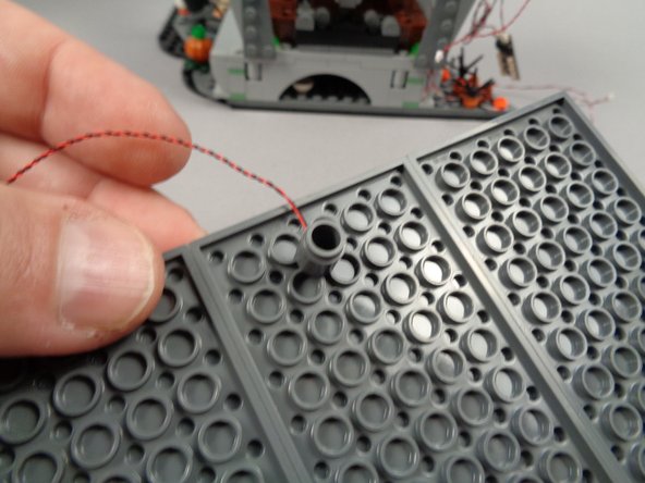 As shown in the photos for this step, attach the round brick to the center rear of the middle plate under the roof.  The light should be positioned at the back of the town hall so it sits above the podium when the roof is re-attached.