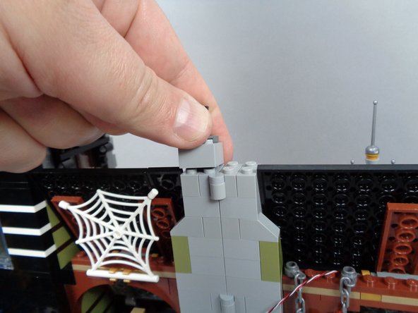 As shown in the two photos for this step, remove the top brick from both sides of the chimney while the mansion is fully open.