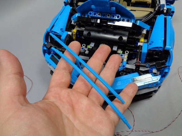 Remove the two blue Technic bars to open up more space under the hood area.  This will make installing the headlights easier.