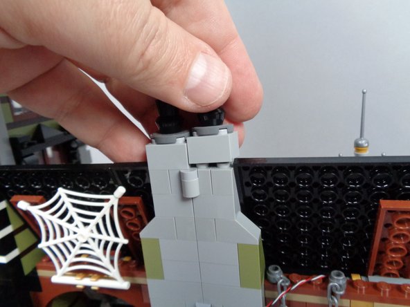 As shown in the two photos for this step, remove the top brick from both sides of the chimney while the mansion is fully open.