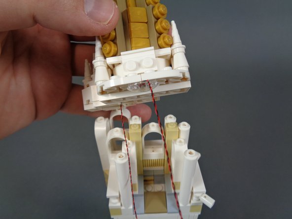 As shown in the second and third photos, carefully re-attach the tower roof.  After the roof has been attached, the two LED light wires should pass out toward the back of the tower as shown in the third photo.
