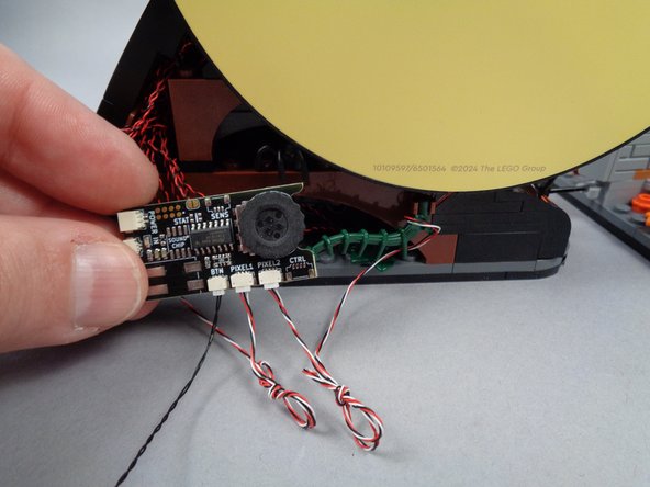 If desired to create a more organized setup, you can coil up the excess wires connecting to the lighting effect controller, and use the two green plant parts to hold the controller in place as shown in the second photo.