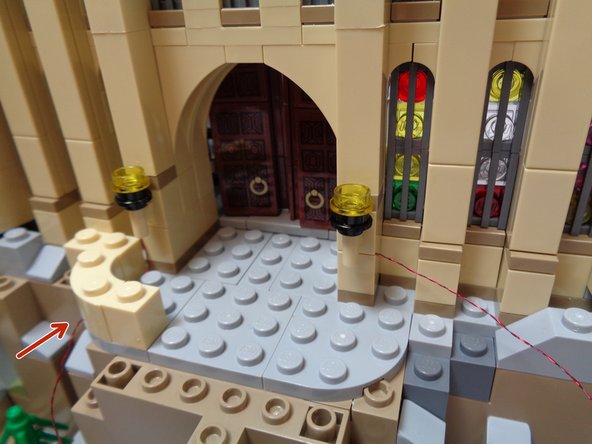 Begin re-attaching the pieces surrounding the castle door as shown in the three photos for this step.