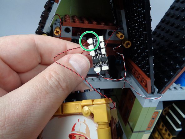 As shown by the green circles in the two photos for this step, connect the two white painting lights (the ones mounted directly behind the explorer painting) to plugs #3 and #4 on the third BRANCH06X adapter board.