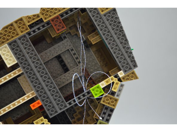 As shown in the second and third photo, wrap the wires several times around the light bluish gray brick close to the rear of the castle.  This provides tension relief and helps keep the wires from scraping when you move your castle.