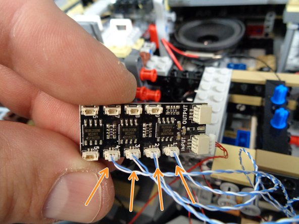 As shown by the four orange arrows in the photo for this step, connect the four docking bay lights to plugs #1, #2, #3, and #4 on the BRANCH09X adapter board.