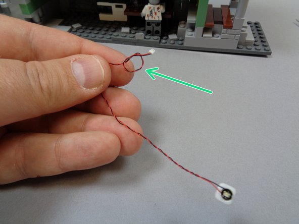 As shown by the green arrow in the second photo, tie a small knot in the wire close to the connecting plug.  This will help you connect the light later.