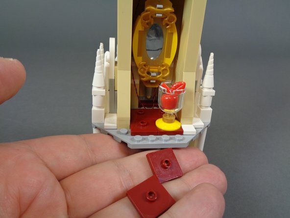 As shown in the first photo, re-attach the dark red 2x2 LEGO jumper plates to the floor of the mirror room.  Note that you will attach the jumper plates one stud forward from the back wall, to allow room for the light wires to pass to the room below.