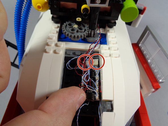 Position the BRANCH09X adapter board in the space behind the roof gears as shown in the first photo for this step.