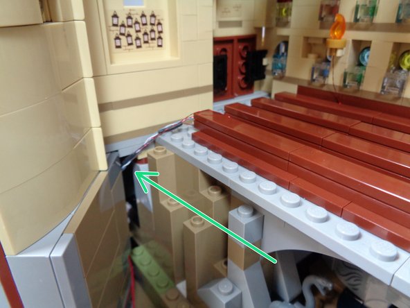 As shown by the green arrow in the second photo, feed the four torch light wires into the gap in the wall below the main hall.