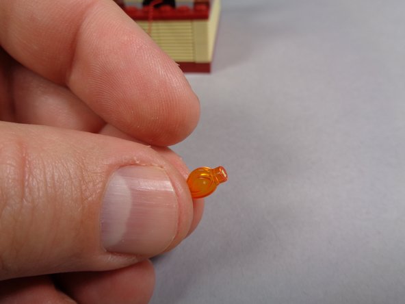 Take the small flame with the tip clipped off from the bag labeled &quot;Core Parts&quot; and press it into the top of the round brown plate as shown in the second and third photos.