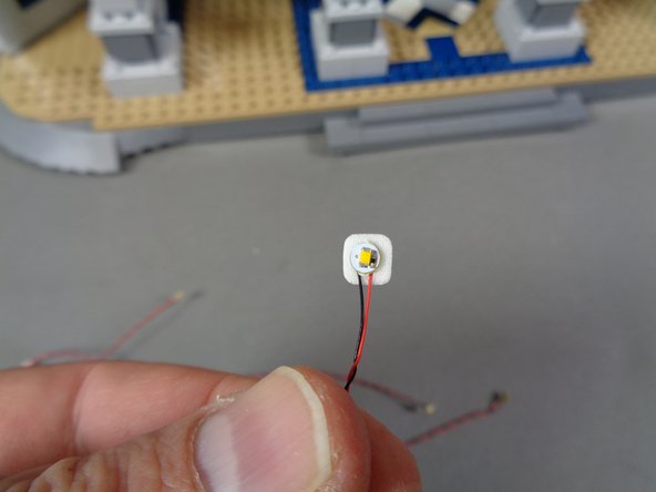 As shown in the second photo, attach one sticky square to the back of each LED light.