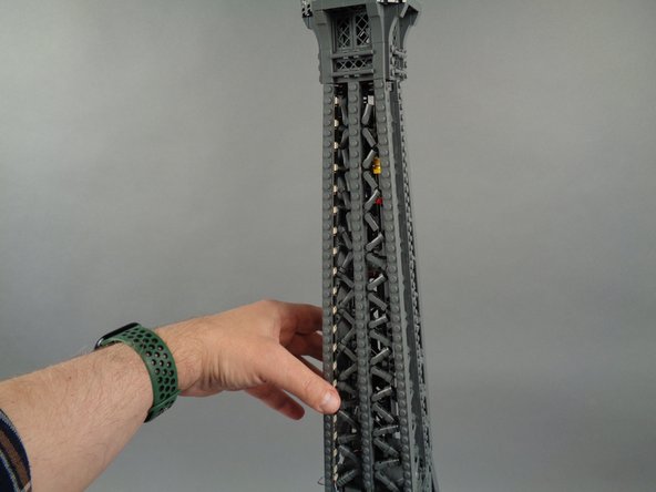 As shown in the photos for this step, attach the top of strip #2 to the tower frame, and re-position brace elements as needed to make room for the LED lights and strip.