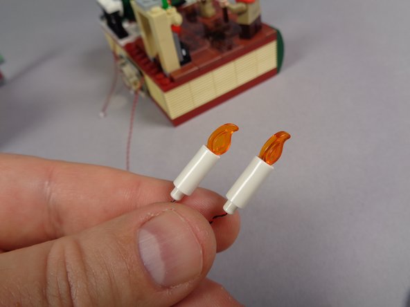As shown in the first photo,  take the two flickering candles from the bag labeled &quot;Orange Lights.&quot;