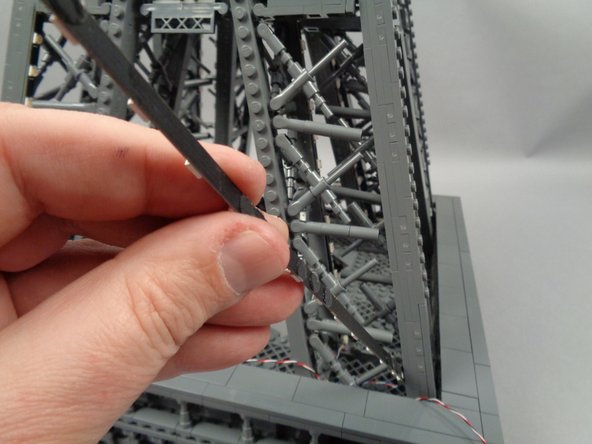 As shown in the first photo for this step, pass the end of the light strip attached to plug #2 of the adapter board into the center of the pillar.