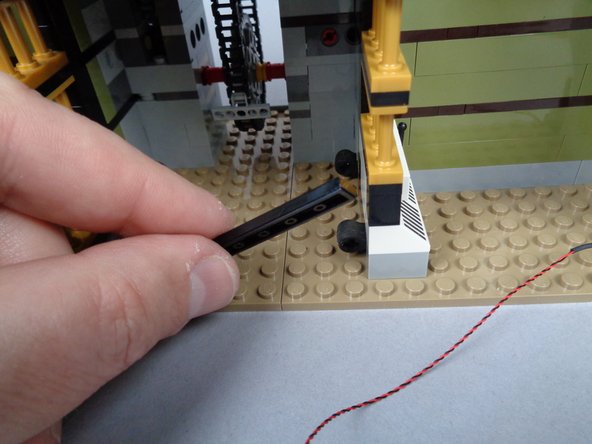 As shown in the first photo for this step, remove the long black LEGO tile in front of the elevator shaft.