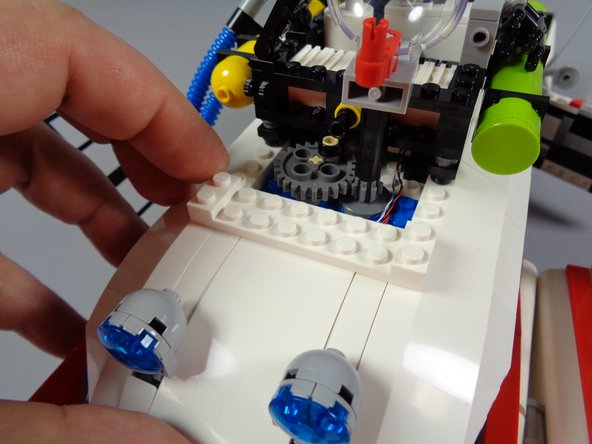 The second photo for this step shows the white plate re-attached, and holding all roof pieces in place.