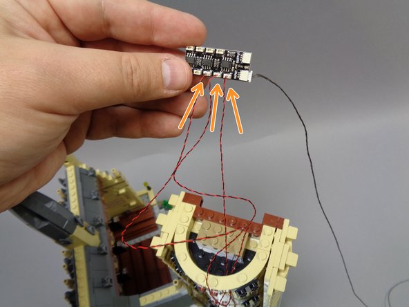 As shown in the second photo, thread the wires for the three staircase lights under the round brick at the top of the tower.  This will hold the wires in place.