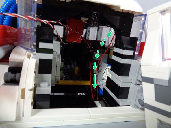 The green arrows in the second photo for this step show the path the wire should take.