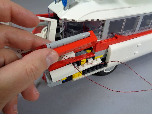 As shown in the photos for this step, re-attach the right tail light assembly, making sure as shown by the green circle in the second photo that the two LED light wires pass toward the outside of the car.