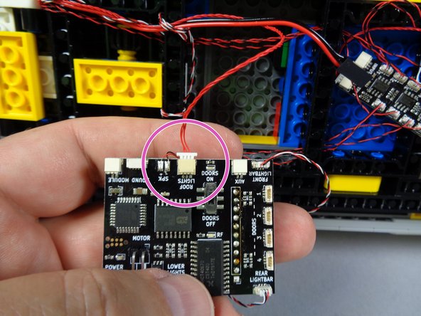 As shown by the purple circle in the photo for this step, connect the red control wire from the roof lights to the ROOF LIGHTS plug on the main controller.