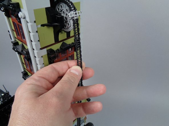 As shown in the photos for this step, disconnect the elevator chain and let it fall away from the upper tower section.