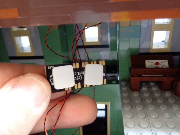As shown in the first photo, place two large sticky squares from Bag 1 on the back of the BRANCH09X adapter board.