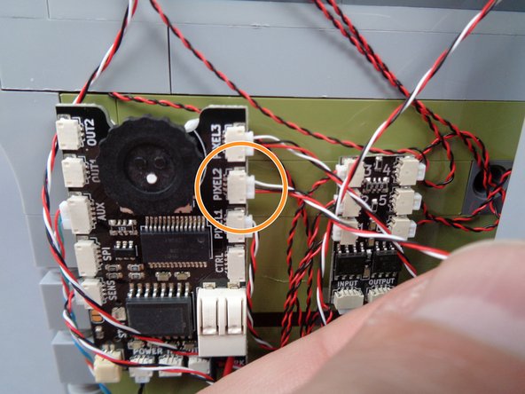 As shown by the orange arrow and circle in the photos for this step, connect the light strip wire to the plug labeled &quot;PIXEL2&quot; on the main effect controller.