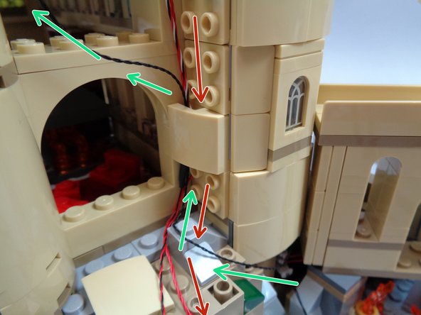 As shown in the second photo, gather the two control wires coming from the top of the towers and pass them DOWN the channel you created by removing the tan slopes. (see the red arrows in the photo)