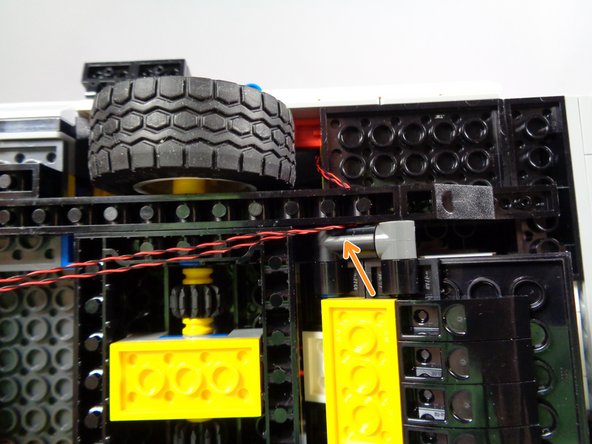 This is a tight space, because of the ramp frame parts immediately behind the Technic frame.  You may find this process easier to complete if you open the ramp before passing the wires.