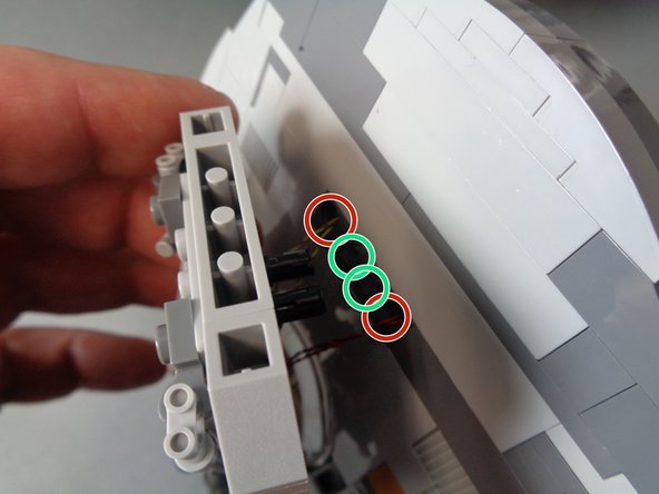 As shown in the first photo, re-attach the laser cannon to the main mount, being careful to pull the laser light wires (red circles) through the holes so there is no extra slack sticking out.